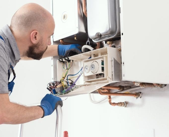 Technician inspecting and servicing internal components of a residential heating system, showcasing professional heater maintenance in Fallbrook and throughout North San Diego County.